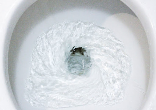 A close-up of water swirling in a toilet as it's being flushed.