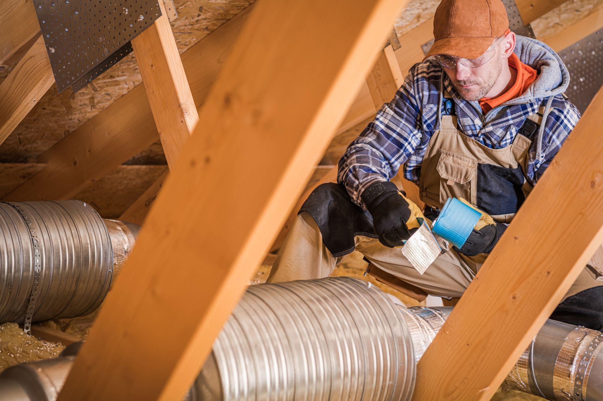 HVAC technician sealing attic ductwork with insulation tape during air duct repair and cleaning service in Las Vegas. 