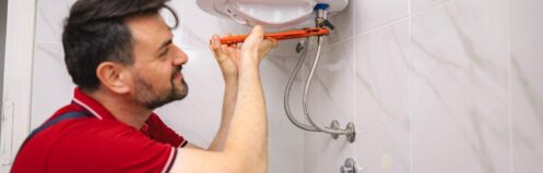 Plumber in Las Vegas repairing a traditional tank water heater during home installation, Pure Plumbing & Air providing expert water heater service.