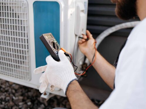 Henderson NV HVAC technician inspecting an AC capacitor on a residential outdoor unit