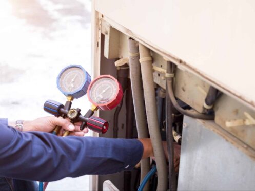 Licensed HVAC technician inspecting AC refrigerant lines in a Paradise NV home