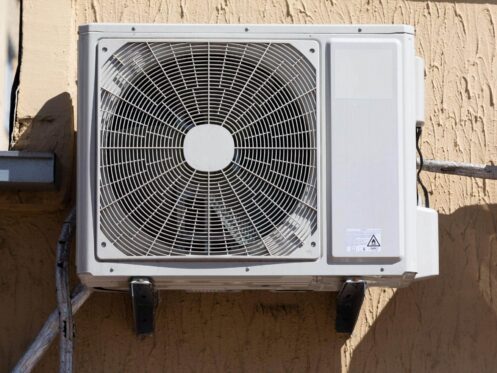 Older central AC condenser unit outside a Las Vegas home with desert landscaping